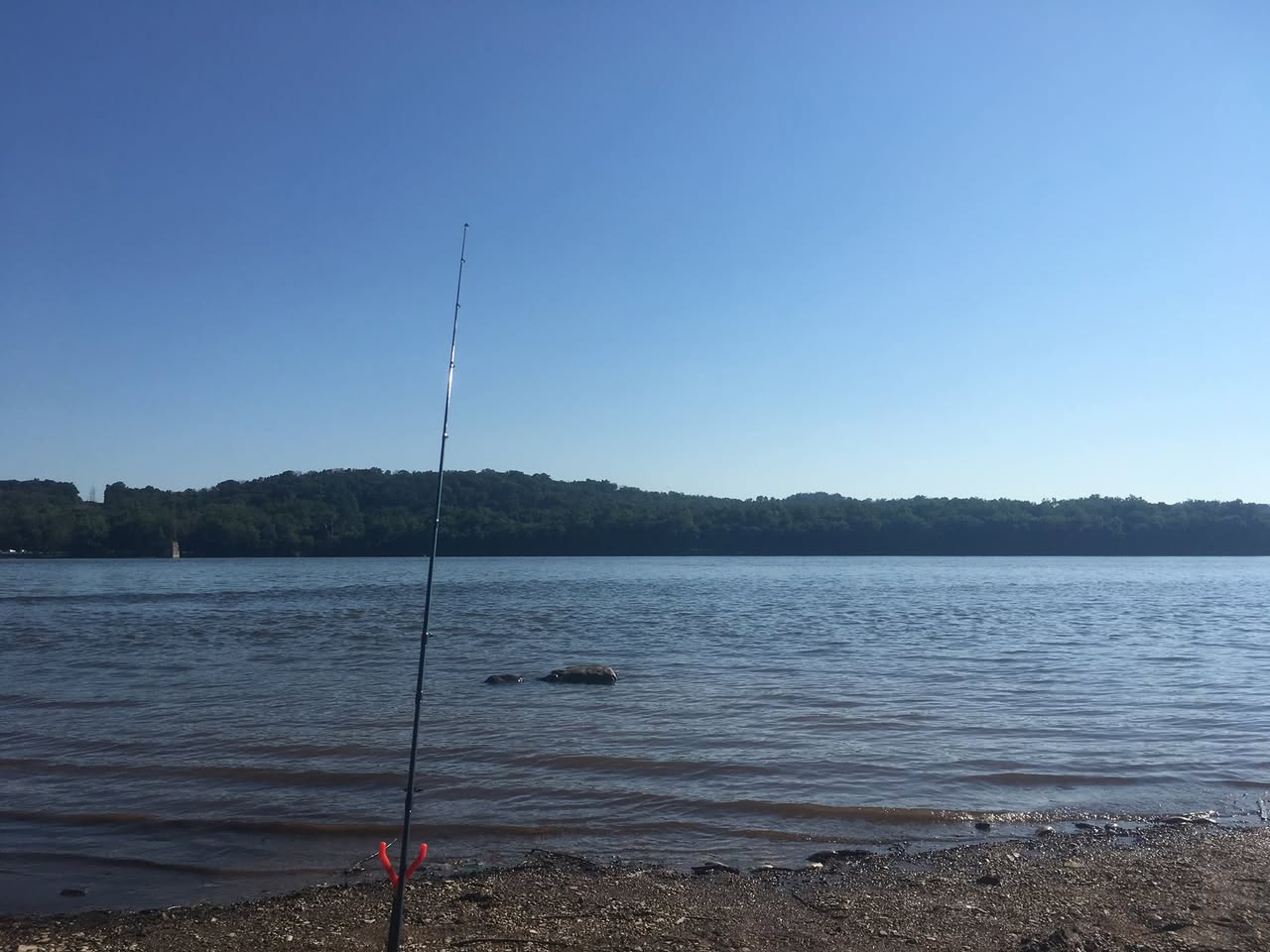 Fishing landscape: rod on river bank, scenic, no people